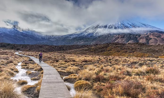 Start of the Tongariro Alpine Crossing trail in Tongariro National Park, New Zealand, with mountainous landscape in the background