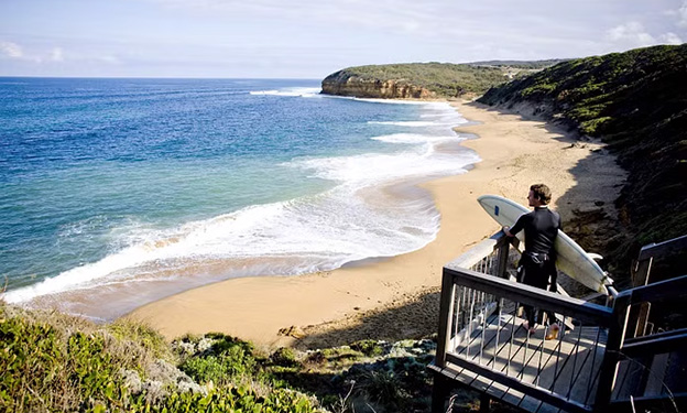 Man with surfboard overlooking the beach in Torquay, Victoria